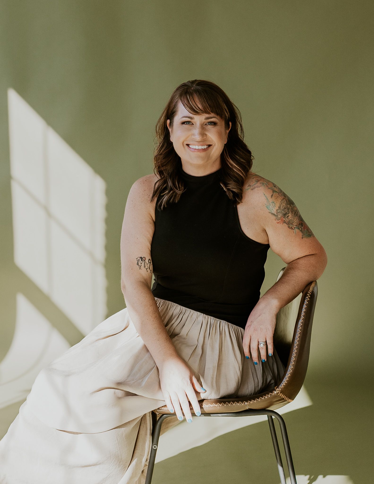 A woman sitting in a chair in a studio and smiling.