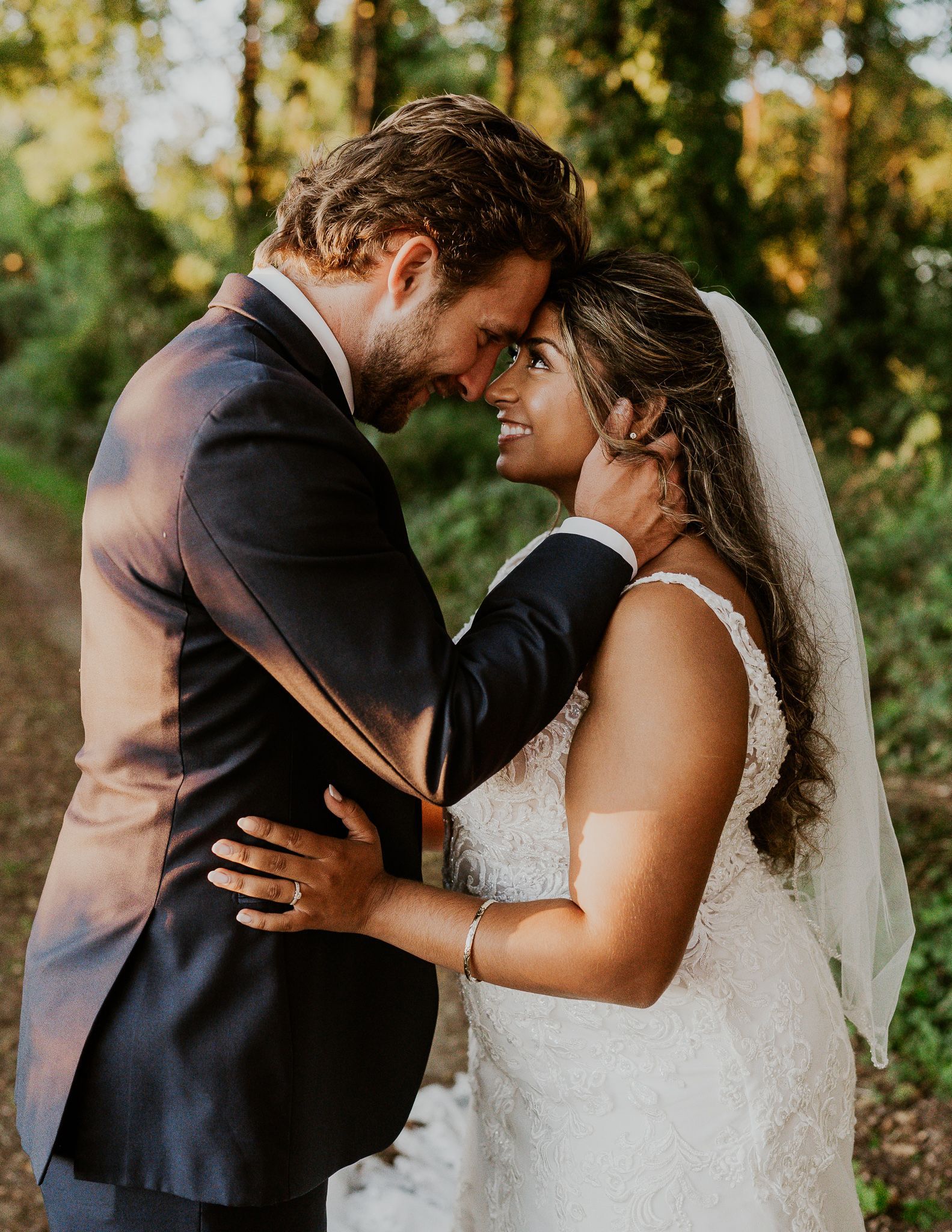 A bride and groom are standing next to each other in front of a window holding a bouquet of flowers.
