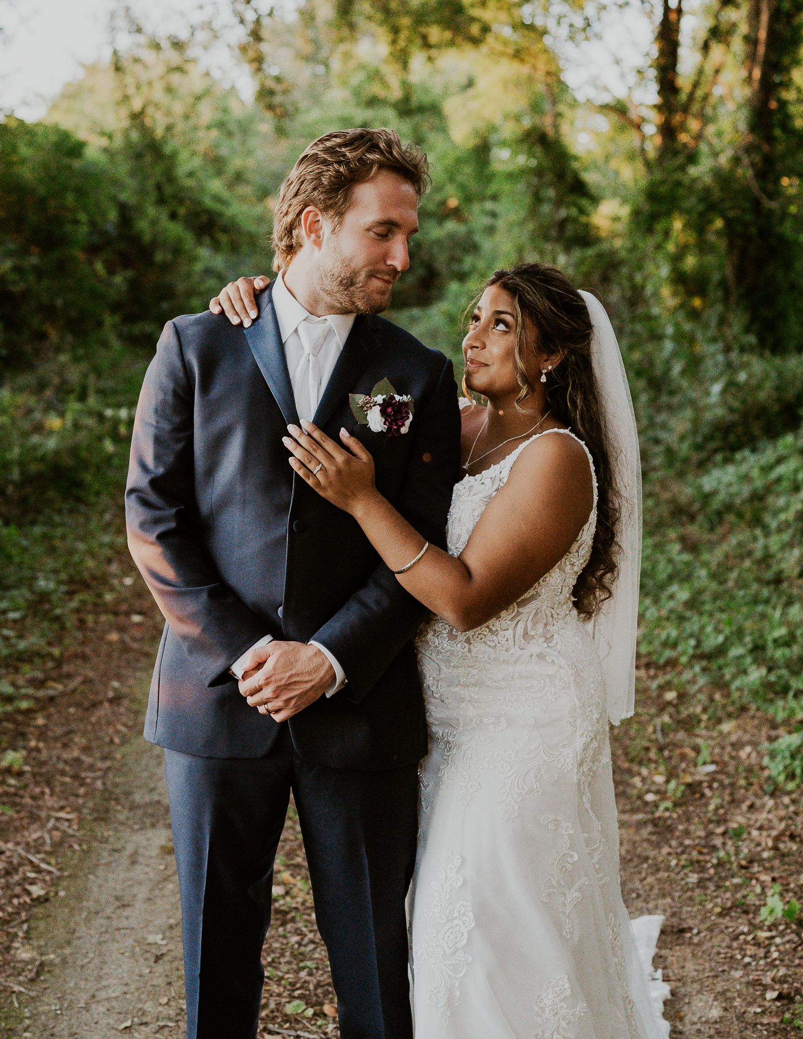 a bride and groom are standing next to each other in front of a window holding a bouquet of flowers .