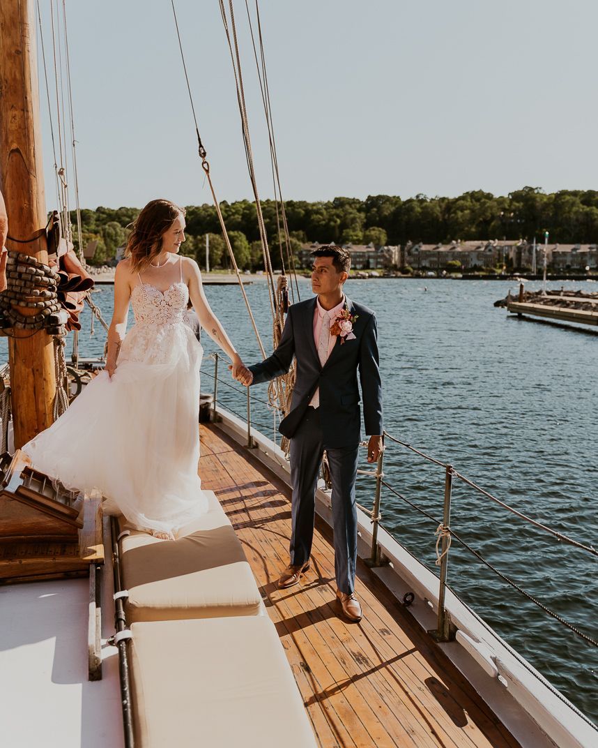 A bride and groom are walking on a boat holding hands.