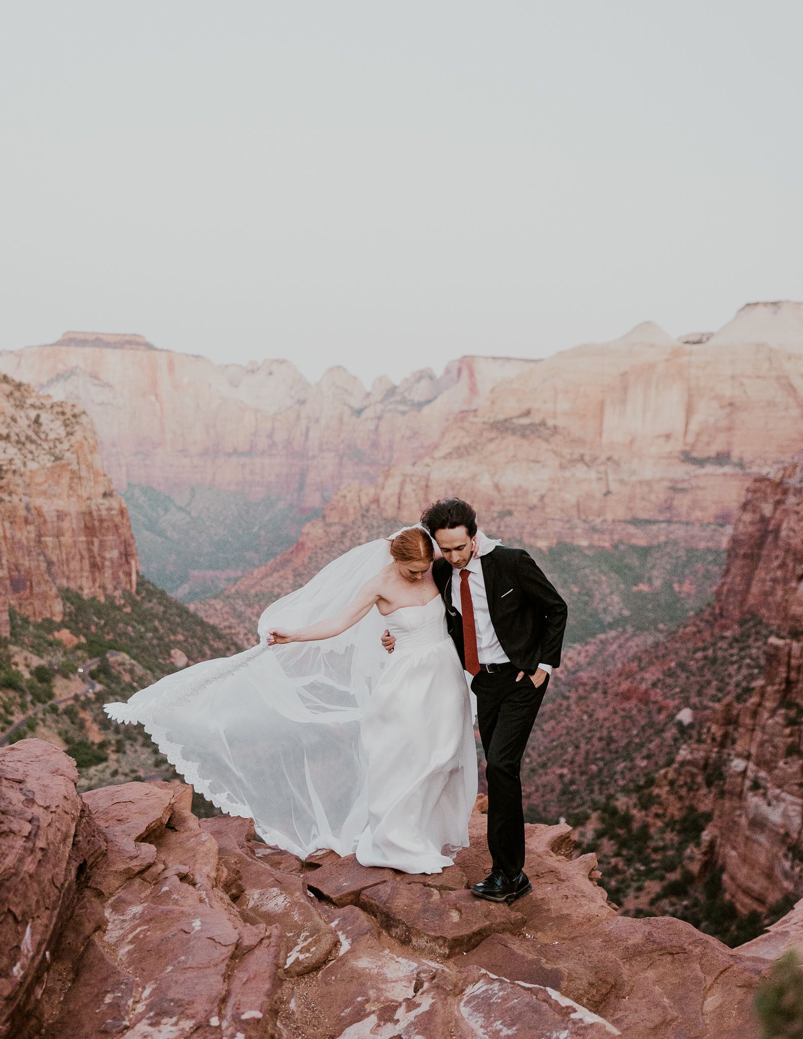 A bride and groom are sitting on the deck of a sailboat.