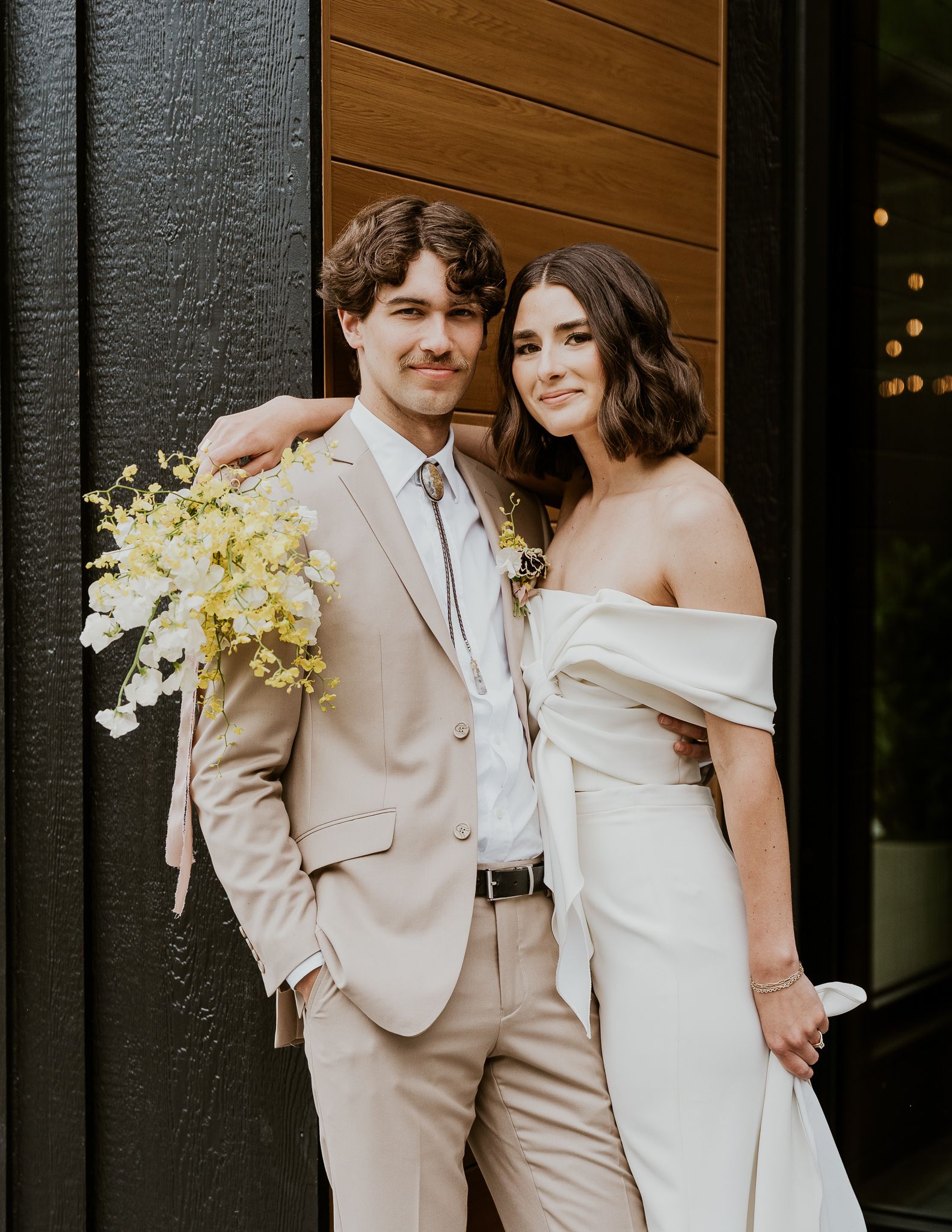 A bride and groom are standing next to each other holding drinks.