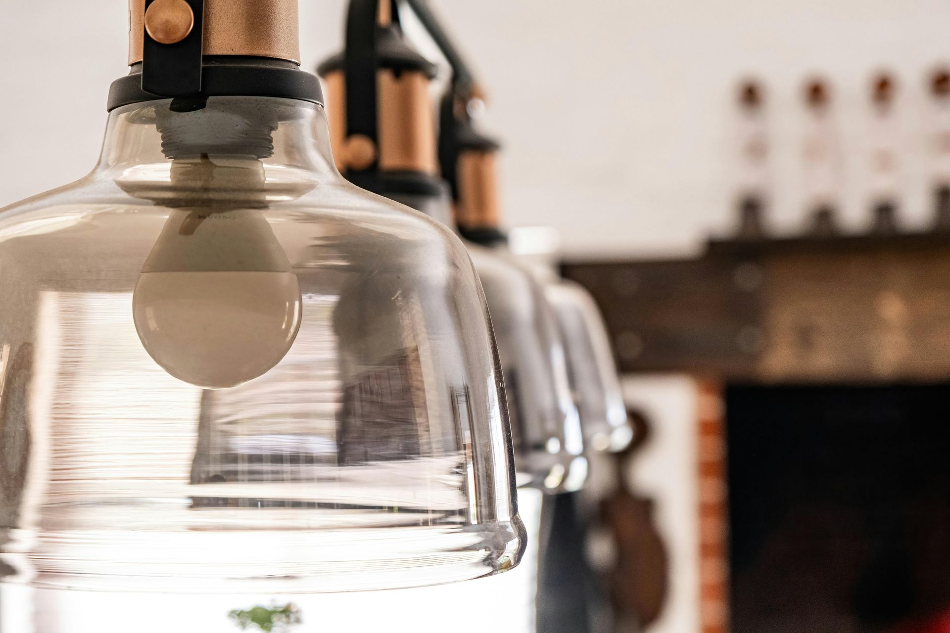 Man in yellow hard hat drills wood on a table outdoors near a wooden structure.