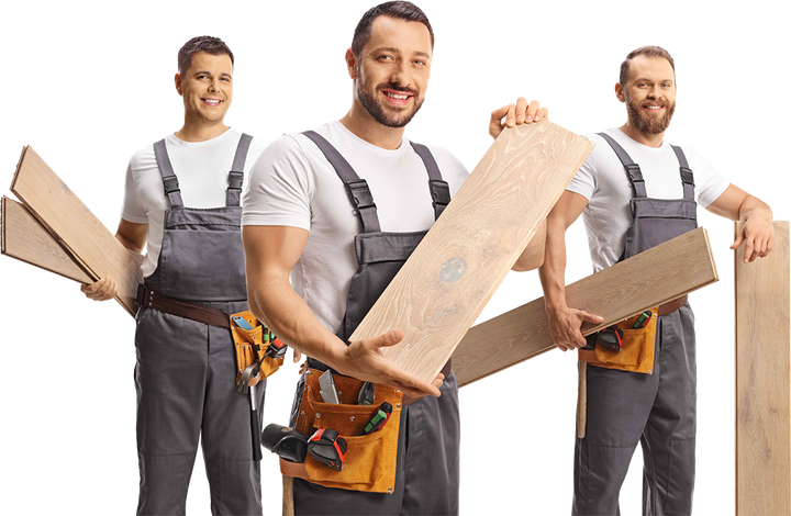 Three workers holding wooden planks, smiling, wearing gray overalls and white shirts.