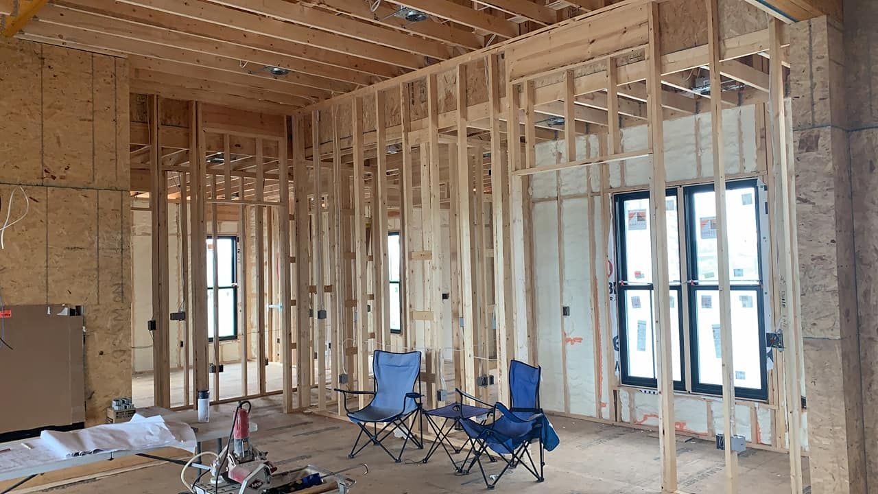 A room in a house under construction with chairs and windows.