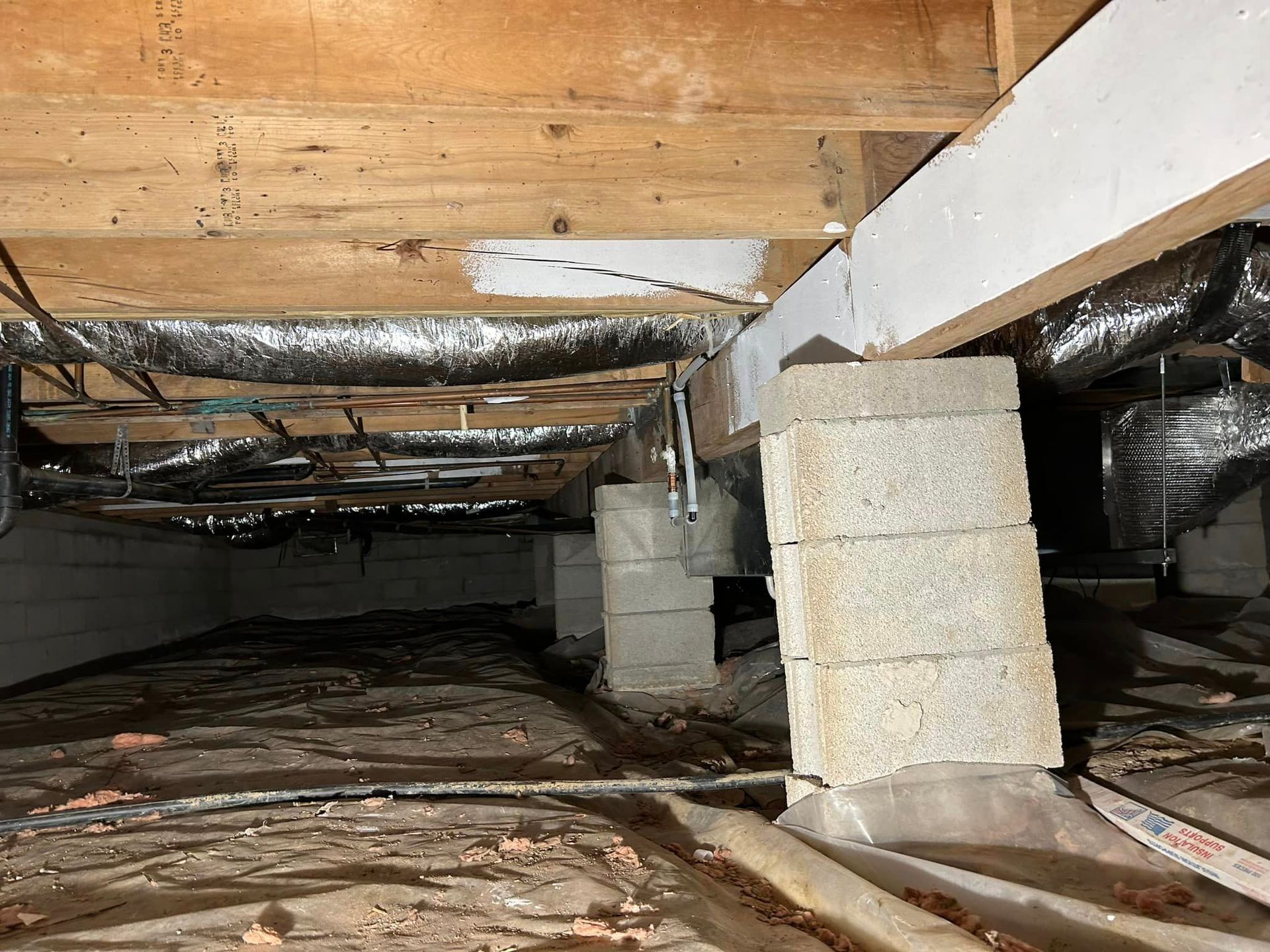 A crawl space under a house with a lot of wood and bricks.