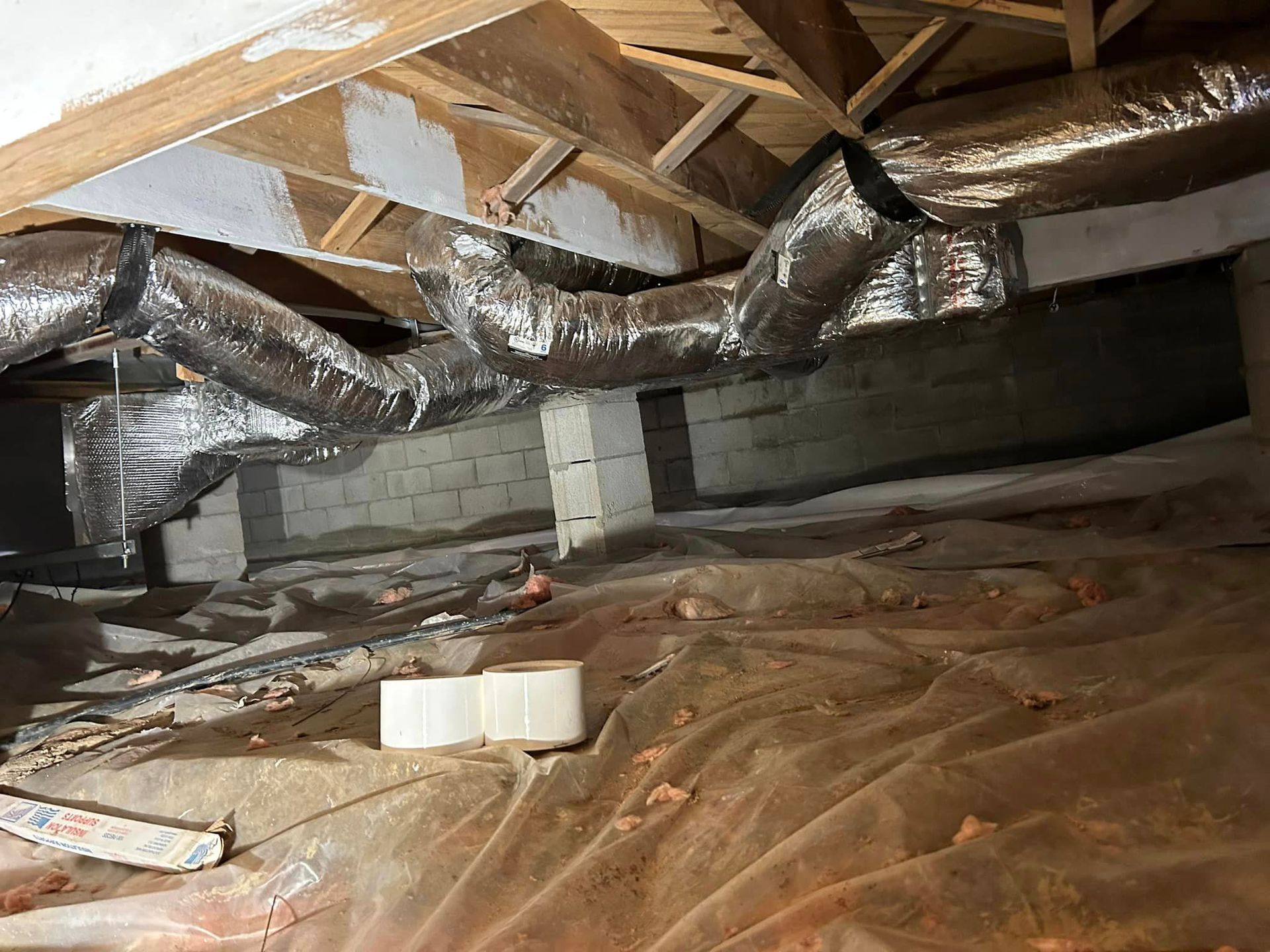 A basement with a lot of ducts hanging from the ceiling.