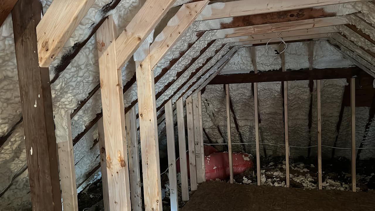 An attic with wooden beams and foam on the ceiling.
