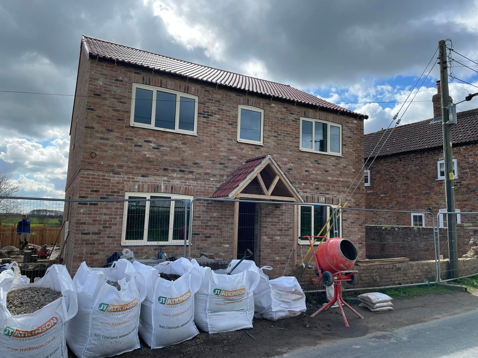 A brick house is being built with bags of dirt in front of it.