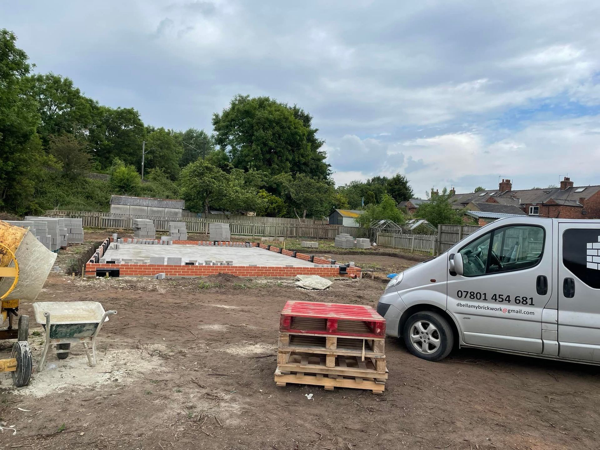 A van is parked in a construction site next to a cement mixer.