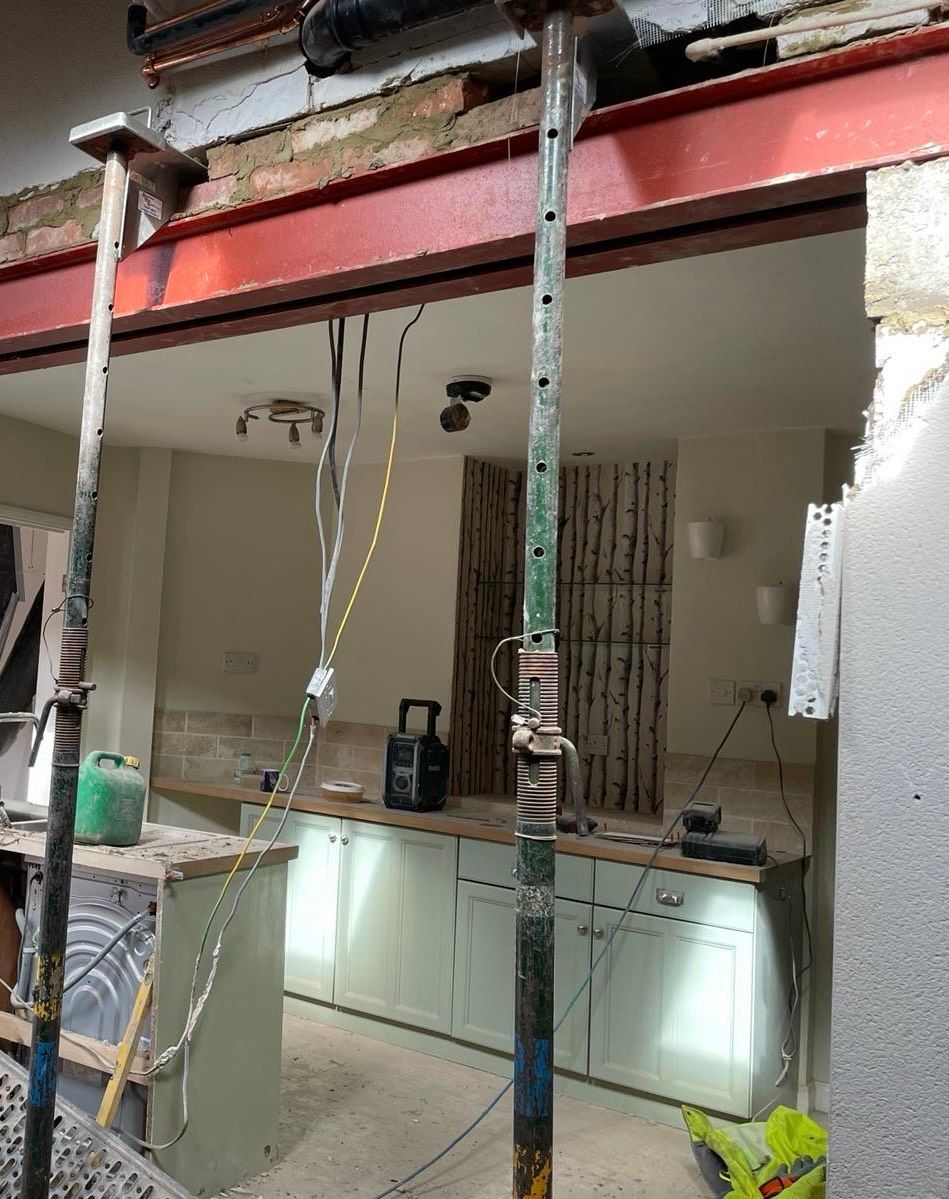 A kitchen under construction with scaffolding and a brick wall.