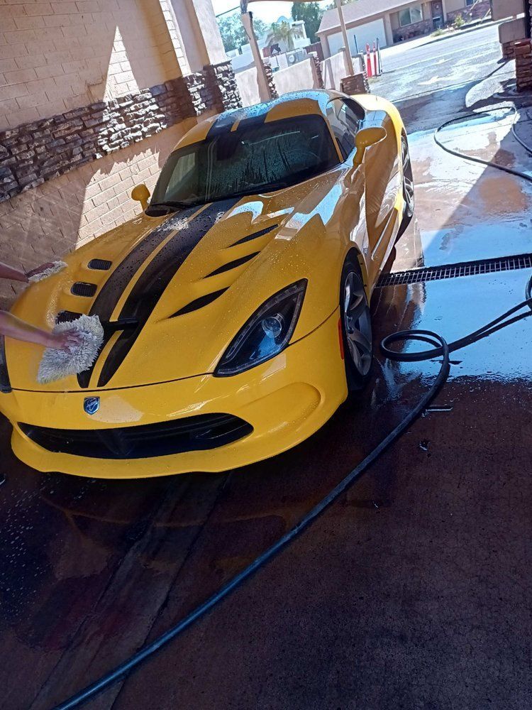 A yellow sports car is being washed in a car wash.