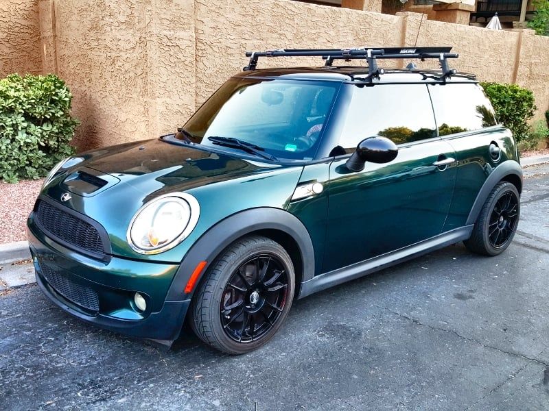 A green mini cooper with a roof rack on it