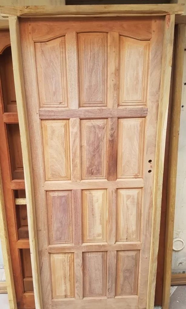 Puerta de madera con paneles, probablemente interiores, veta vertical, color marrón claro, en marco.