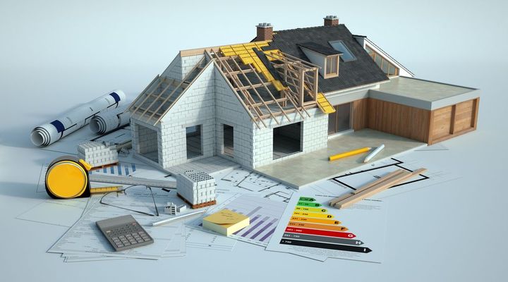 A model of a house under construction is sitting on top of a blueprint.
