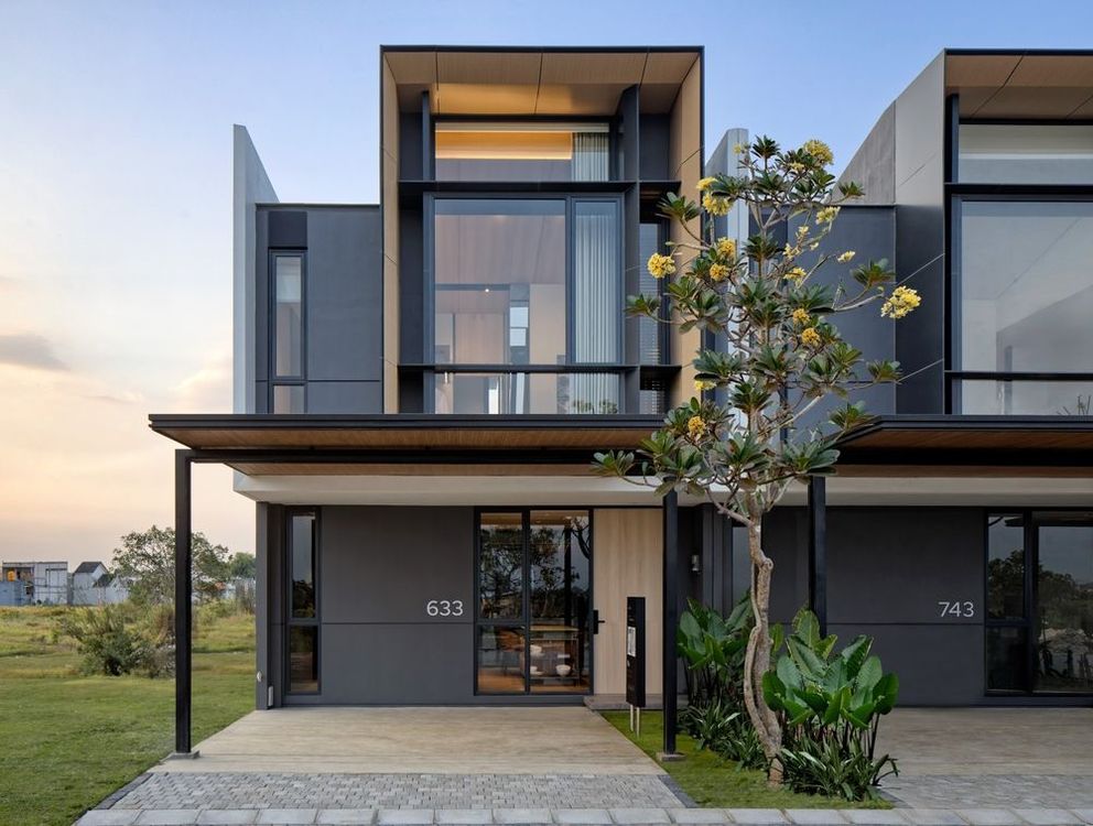 A modern house with a lot of windows and a tree in front of it.