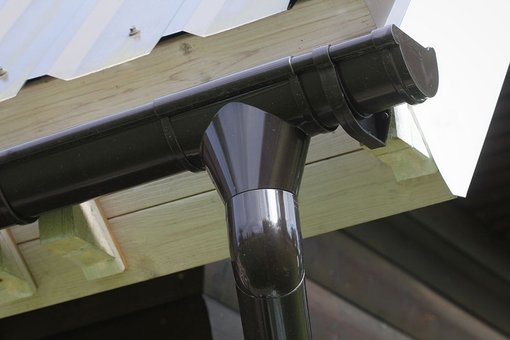 A close up of a black gutter on a wooden roof.
