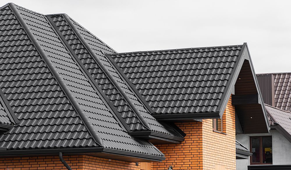 The roof of a brick house with a black tile roof.