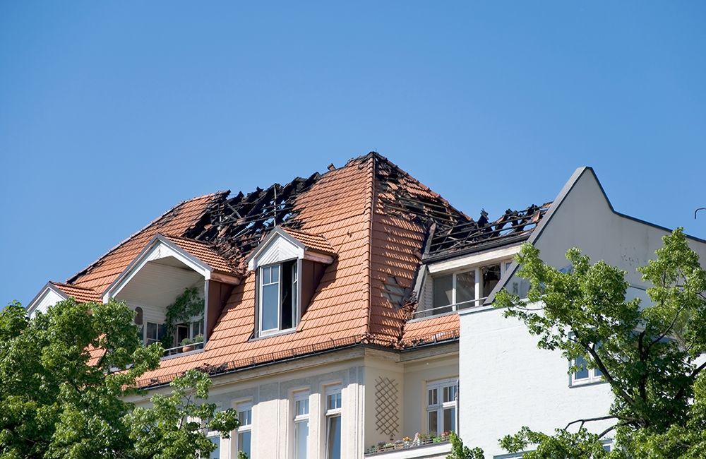 A house with a roof that has been damaged by a fire.