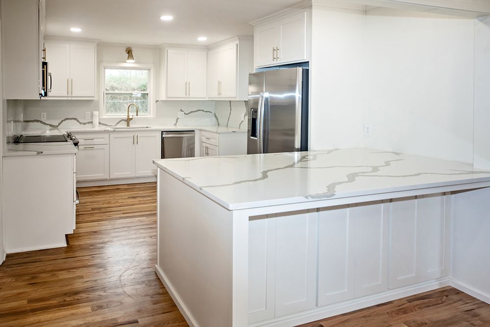A kitchen with white cabinets , stainless steel appliances , and a large island.