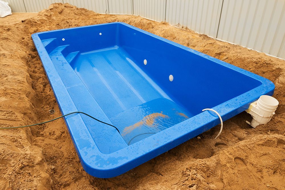 A blue swimming pool is sitting in the dirt.