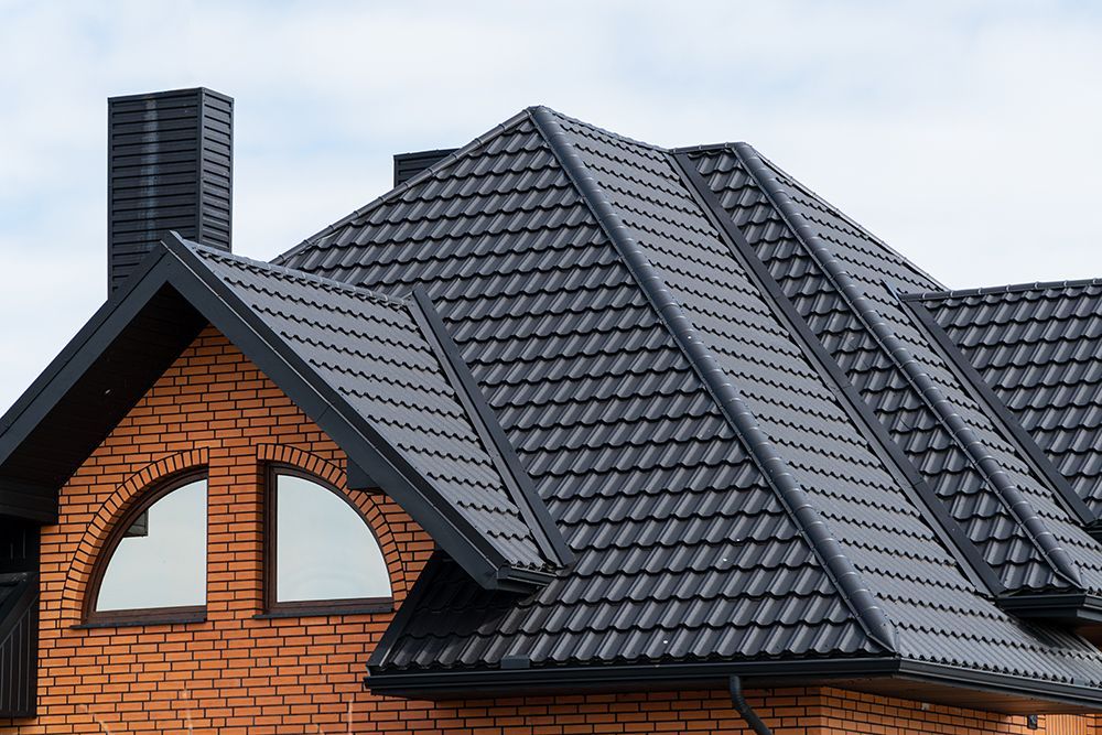 A brick house with a black roof and arched windows.