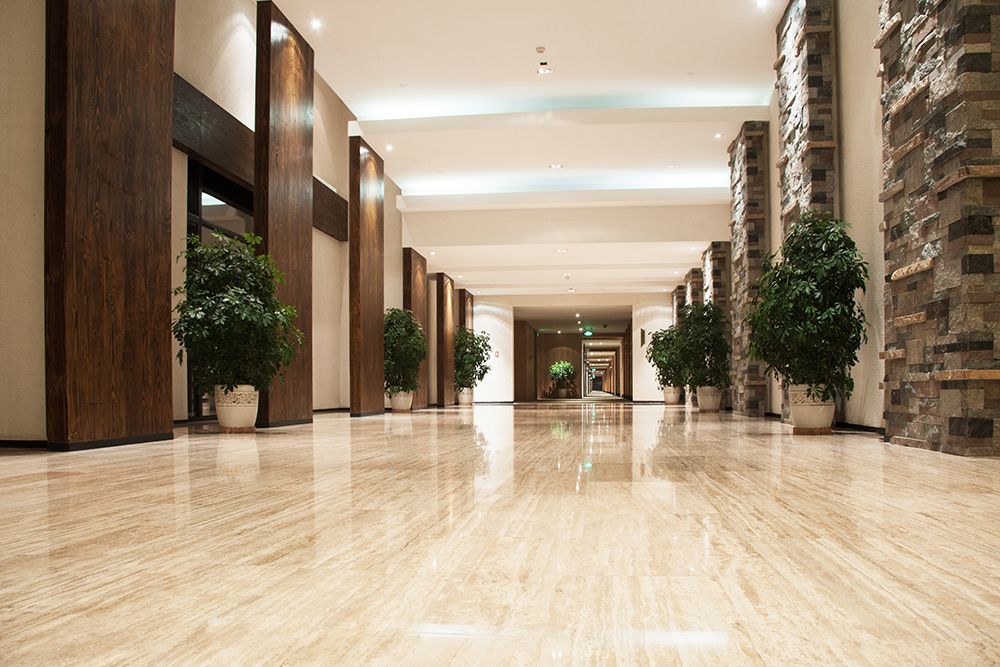 A long hallway with a marble floor and potted plants