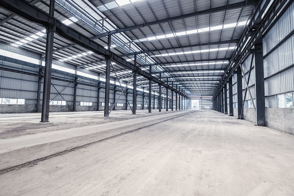 An empty warehouse with a lot of windows and a metal structure.