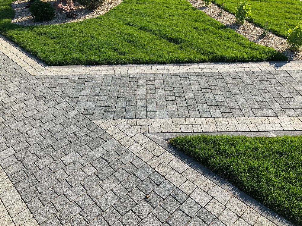 A brick walkway leading to a lush green lawn.