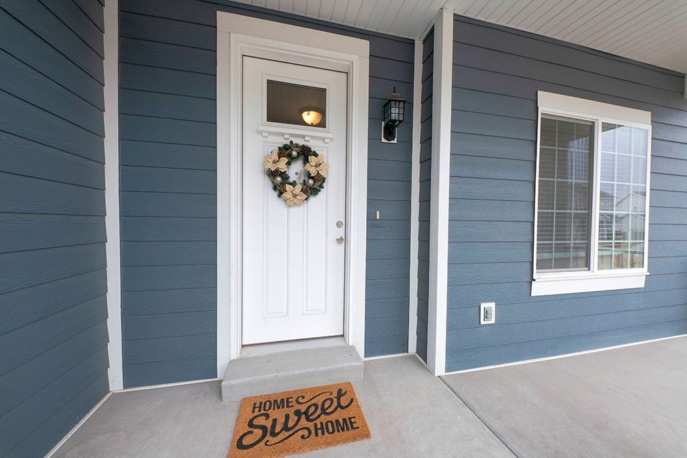 A blue house with a white door and a welcome mat