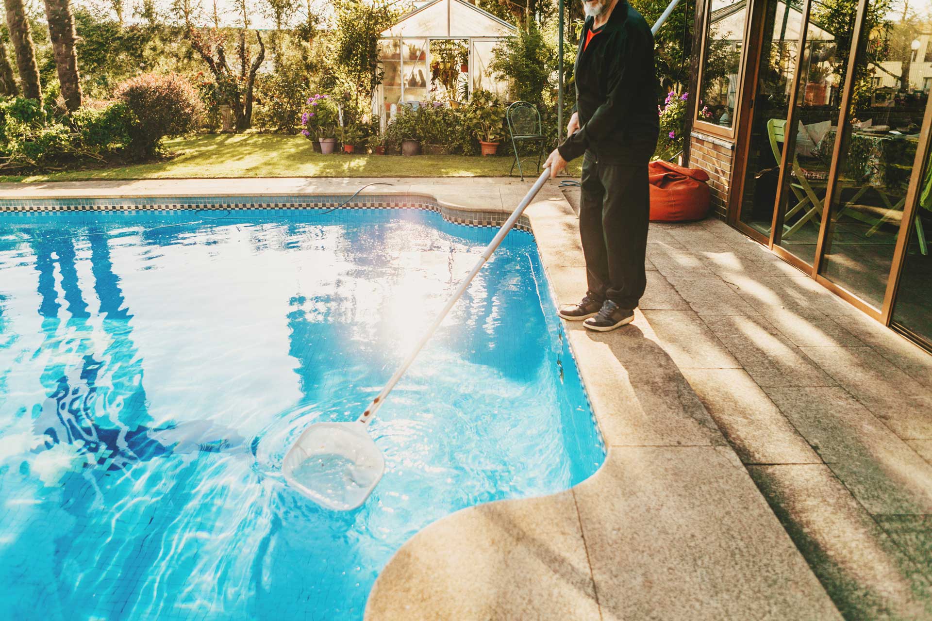 A man with a black uniform cleaning the swimming pool | Penrith, NSW | Ian’s Pools Penrith