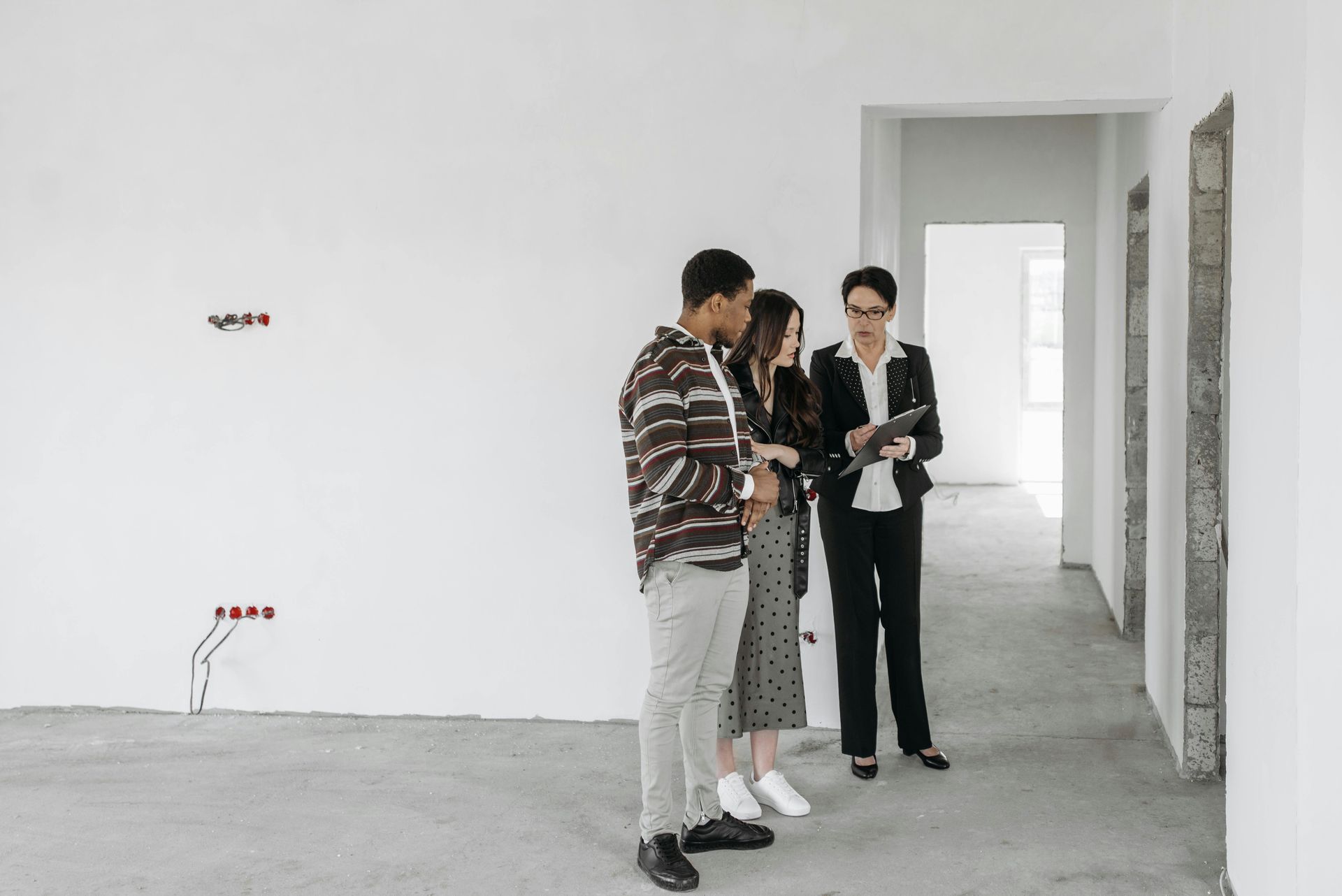 Three people in a sparse white room examining a clipboard together