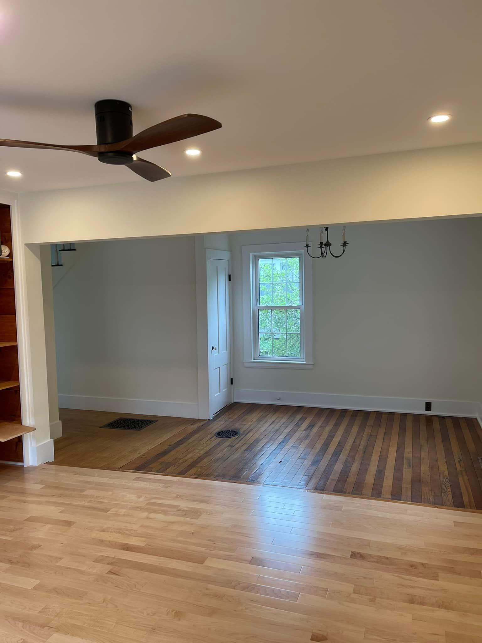 Living room with hardwood floors, ceiling fan, and an arched doorway leading to another room.