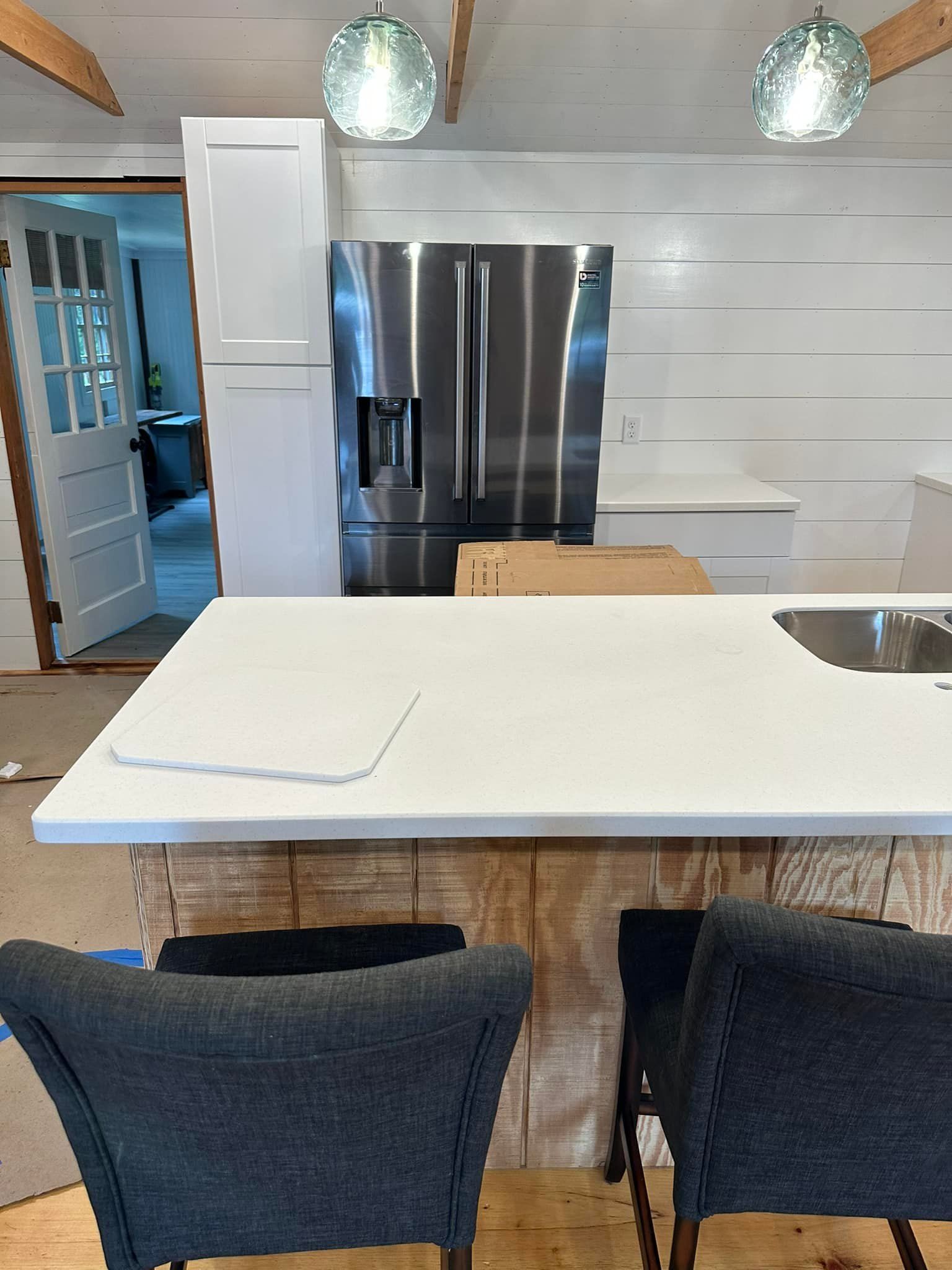 Kitchen with white countertops, stainless steel fridge, and rustic wooden island.