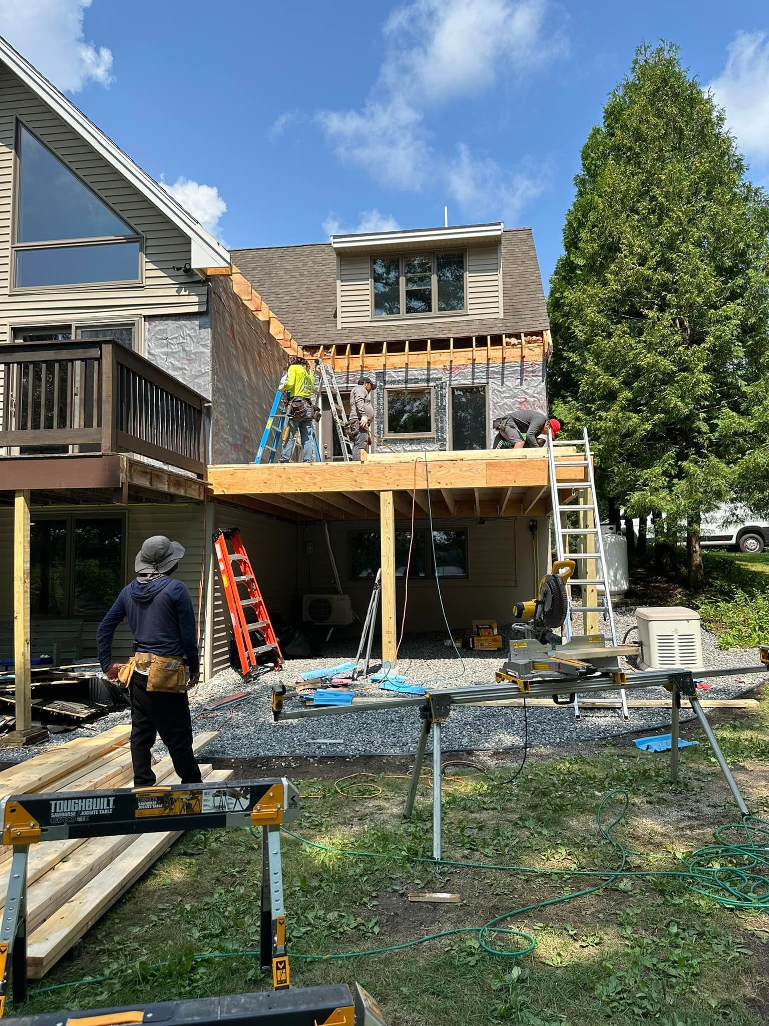 Construction workers on a partially built deck and building. Exterior view, sunny day.