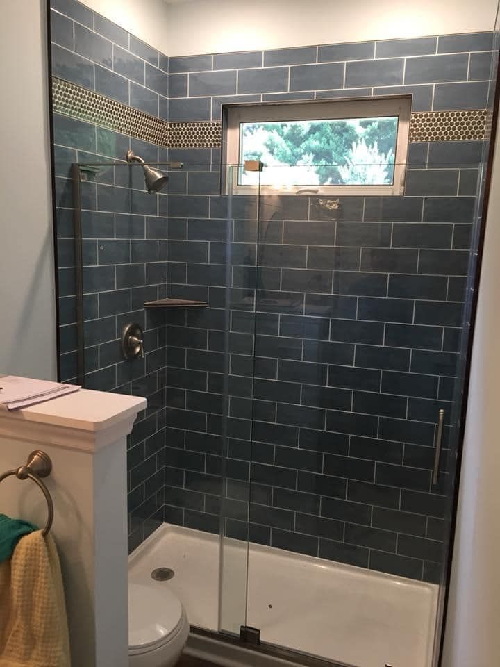 Bathroom shower with blue tiled walls and glass door.