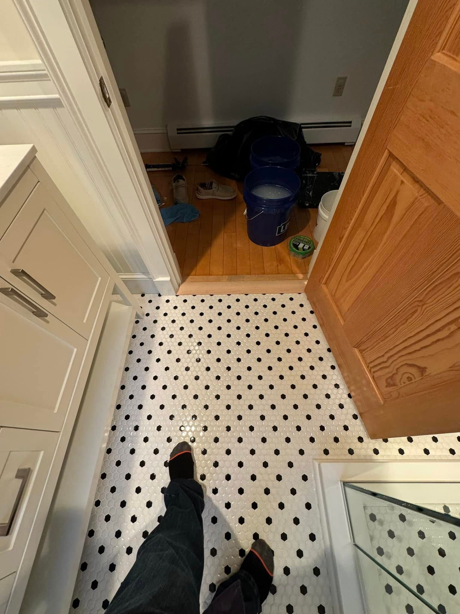 Black and white tiled floor leading to a room with clutter and an open door.