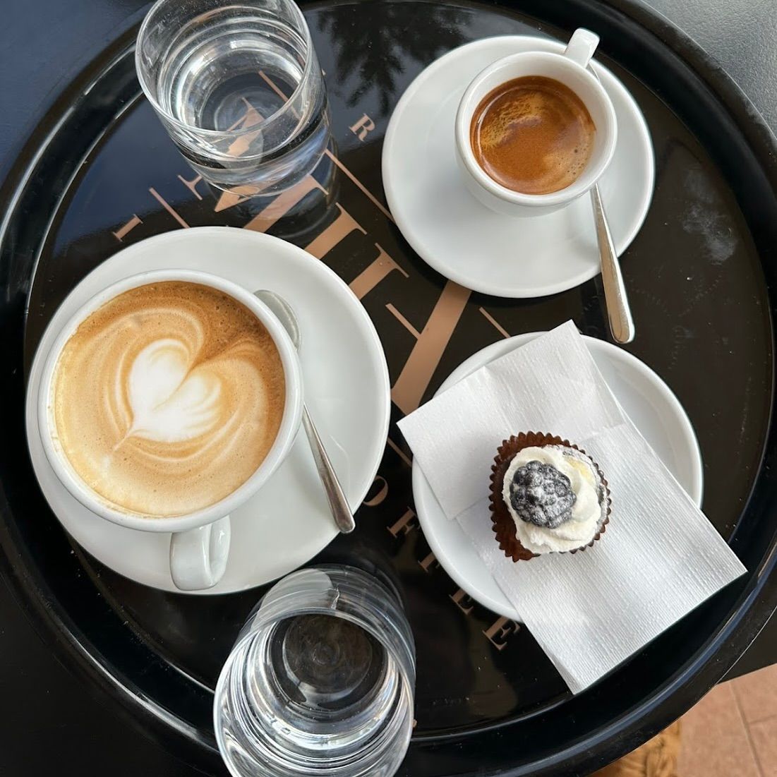 Persona che regge un vassoio di pasticcini, probabilmente croissant, in cucina.