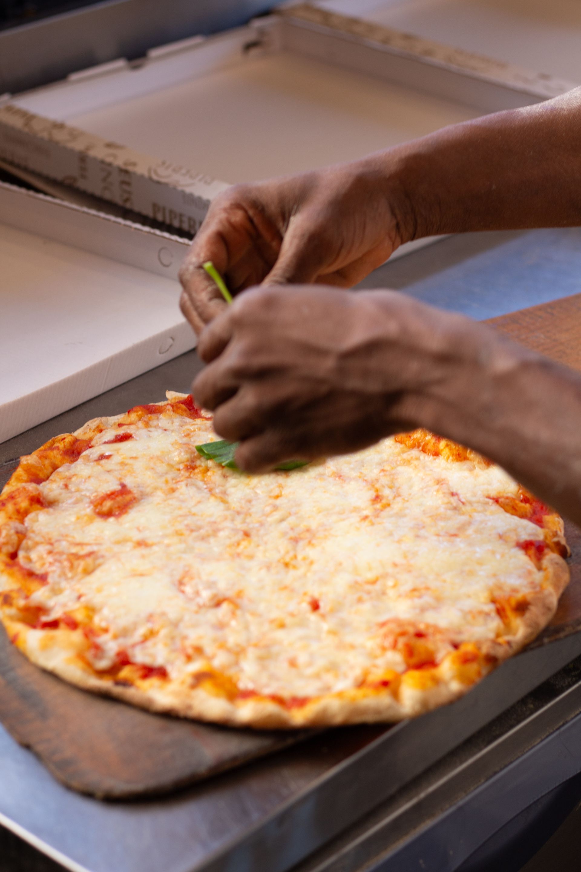 Uno chef che mette del basilico su una pizza al formaggio.