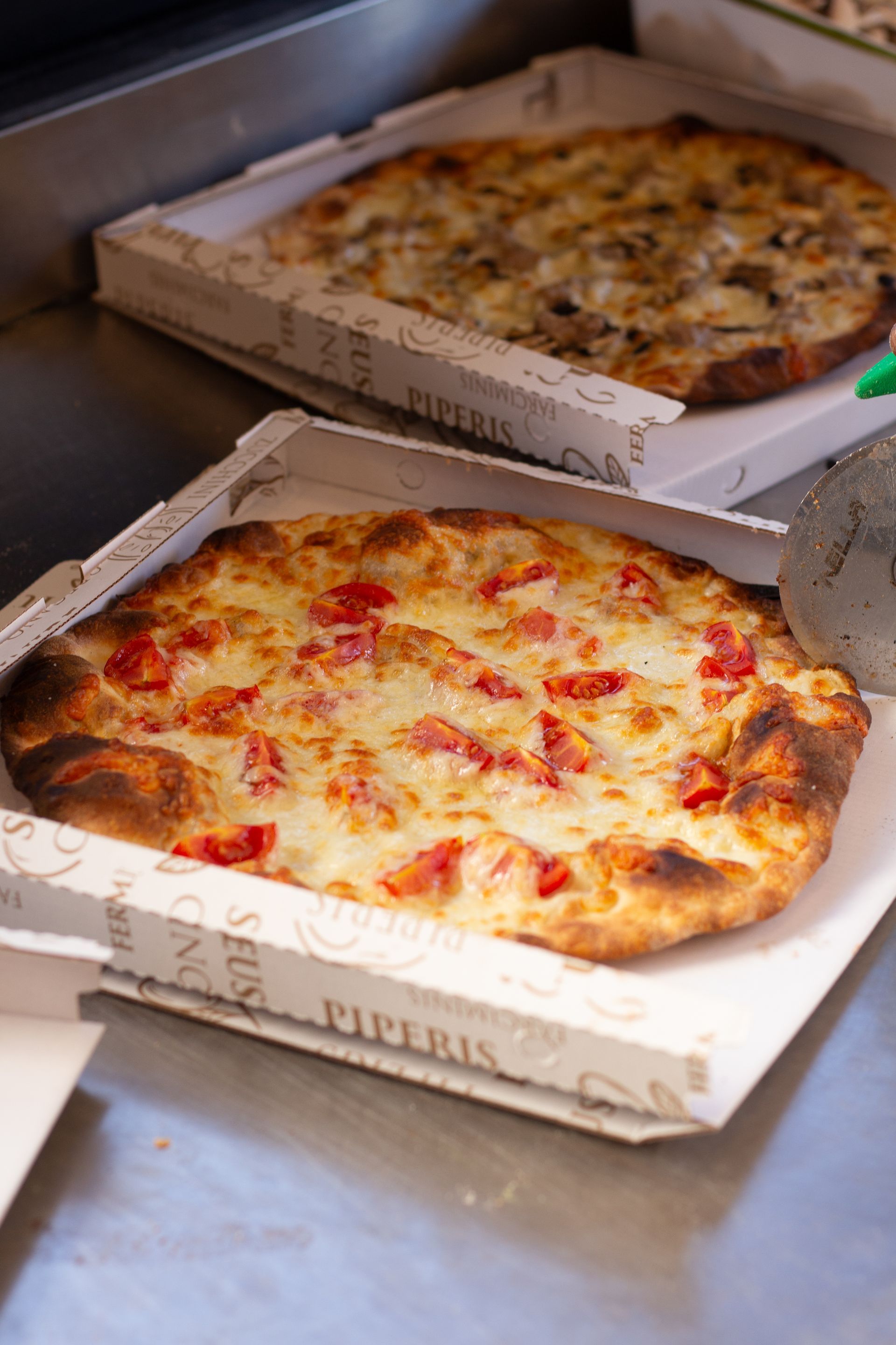 Due pizze in scatole di pizza: una con pomodori e formaggio, l'altra con funghi.