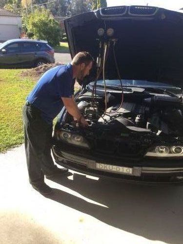 A Man Is Working On The Engine Of A Car With The Hood Open — Airborne Auto Air in The Entrance, NSW