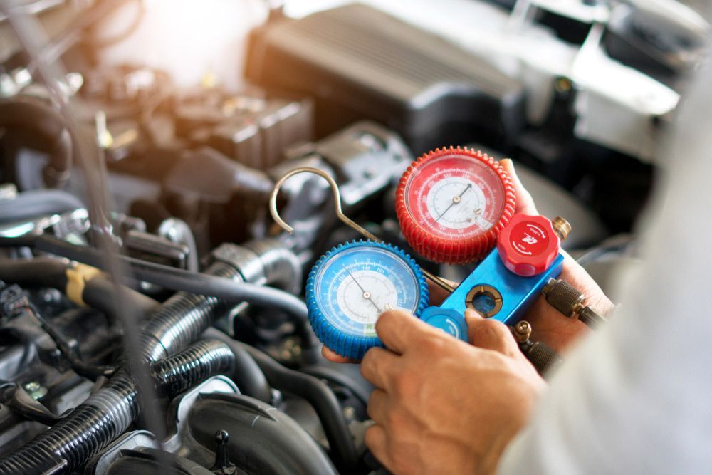 A Close Up Of A Person Holding A Gauge In Front Of A Car Engine — Airborne Auto Air in Wyee, NSW