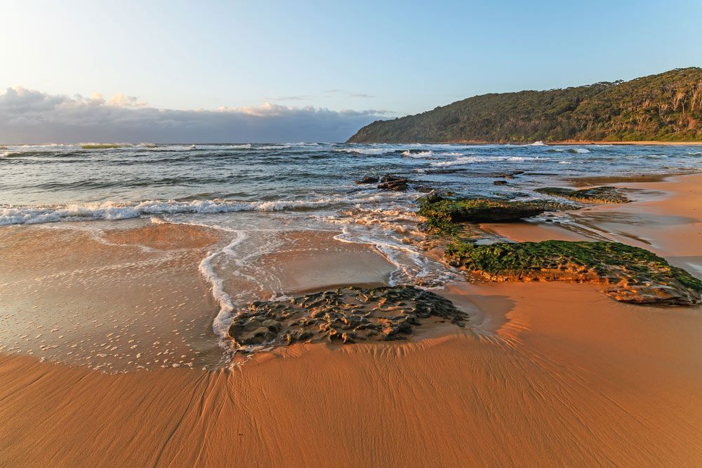 A Sandy Beach With Rocks In The Water And A Mountain In The Background — Airborne Auto Air in Bateau Bay, NSW