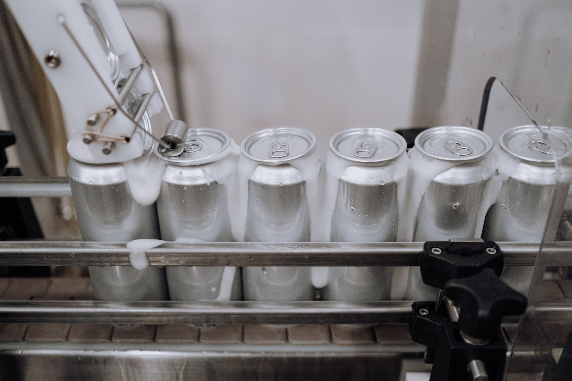 A row of cans are sitting on a conveyor belt.