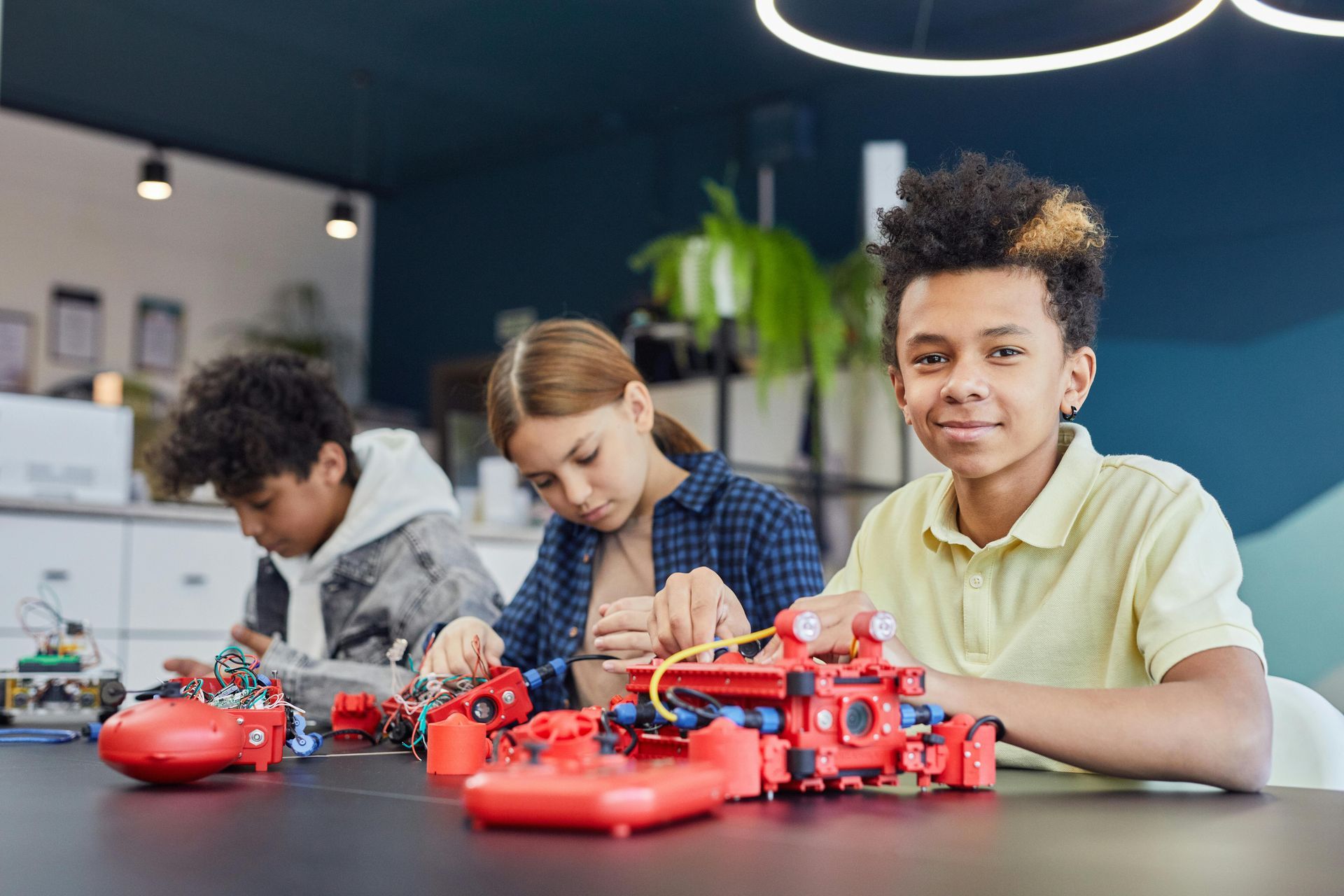 A group of children are sitting at a table working on a robot.