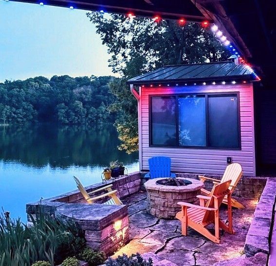 A patio with chairs and a fire pit by a lake