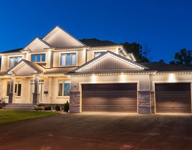 A large house with two garage doors is lit up at night
