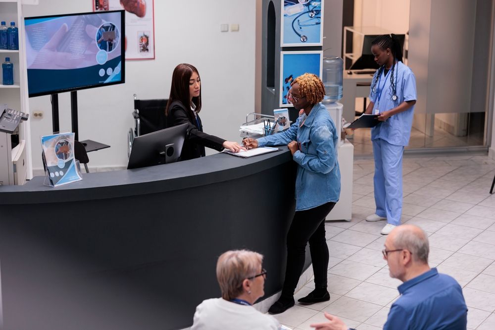 A group of people are standing around a counter in a hospital lobby.