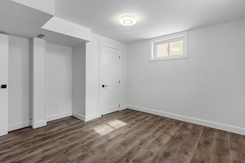 Une pièce vide avec du parquet et des murs blancs.
