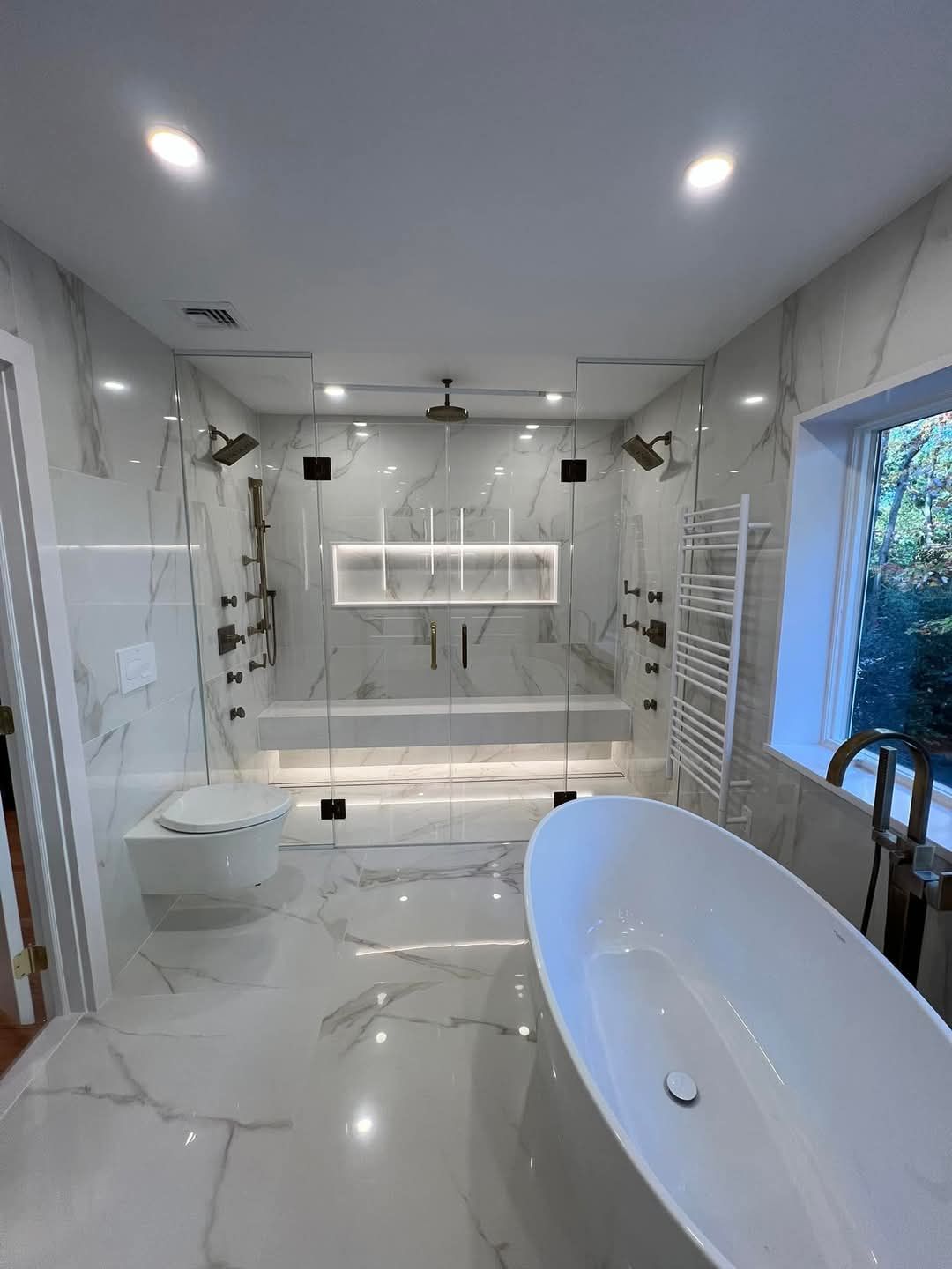 Une salle de bain avec baignoire, WC, douche et fenêtre.